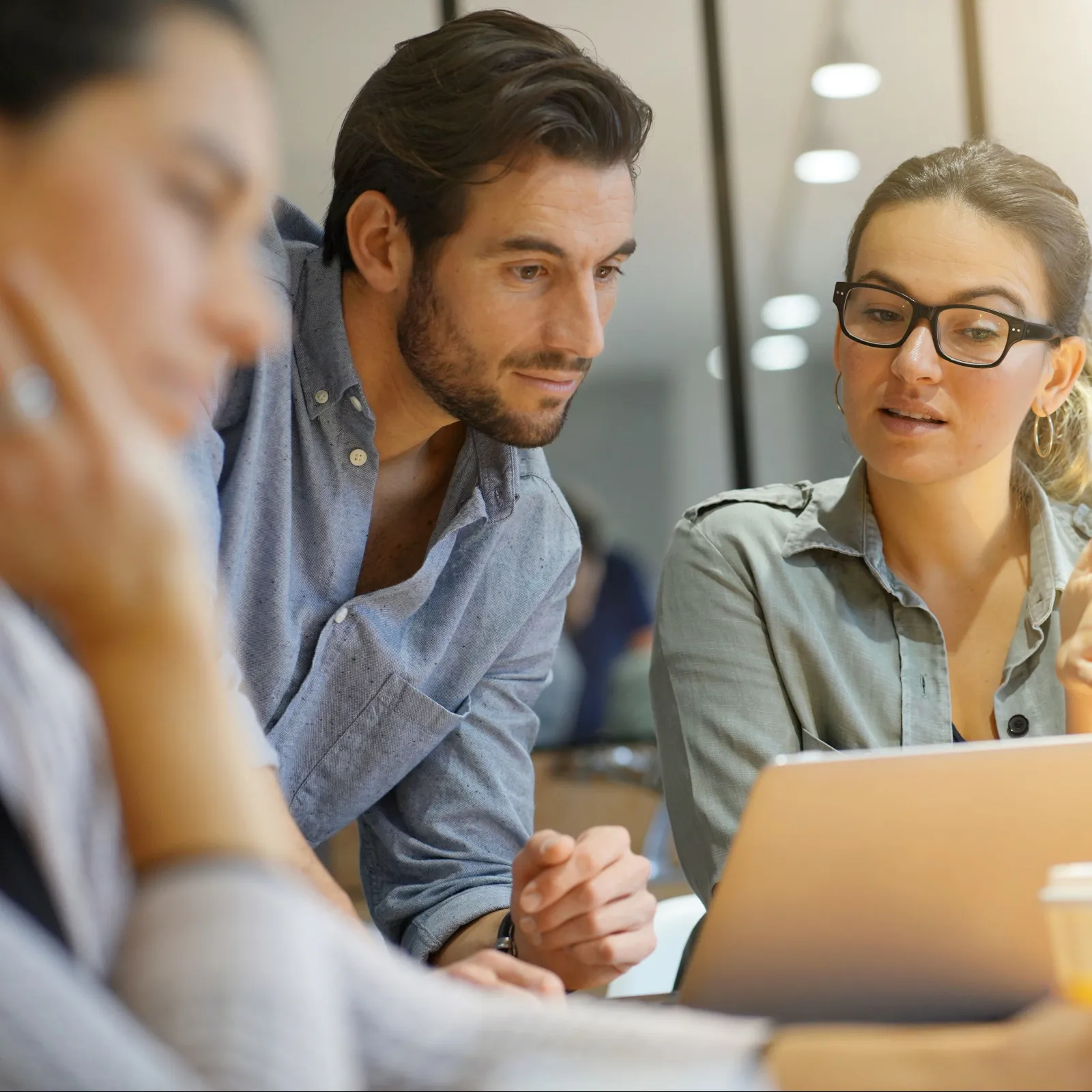 A team discussing ideas around a laptop in a modern office environment.