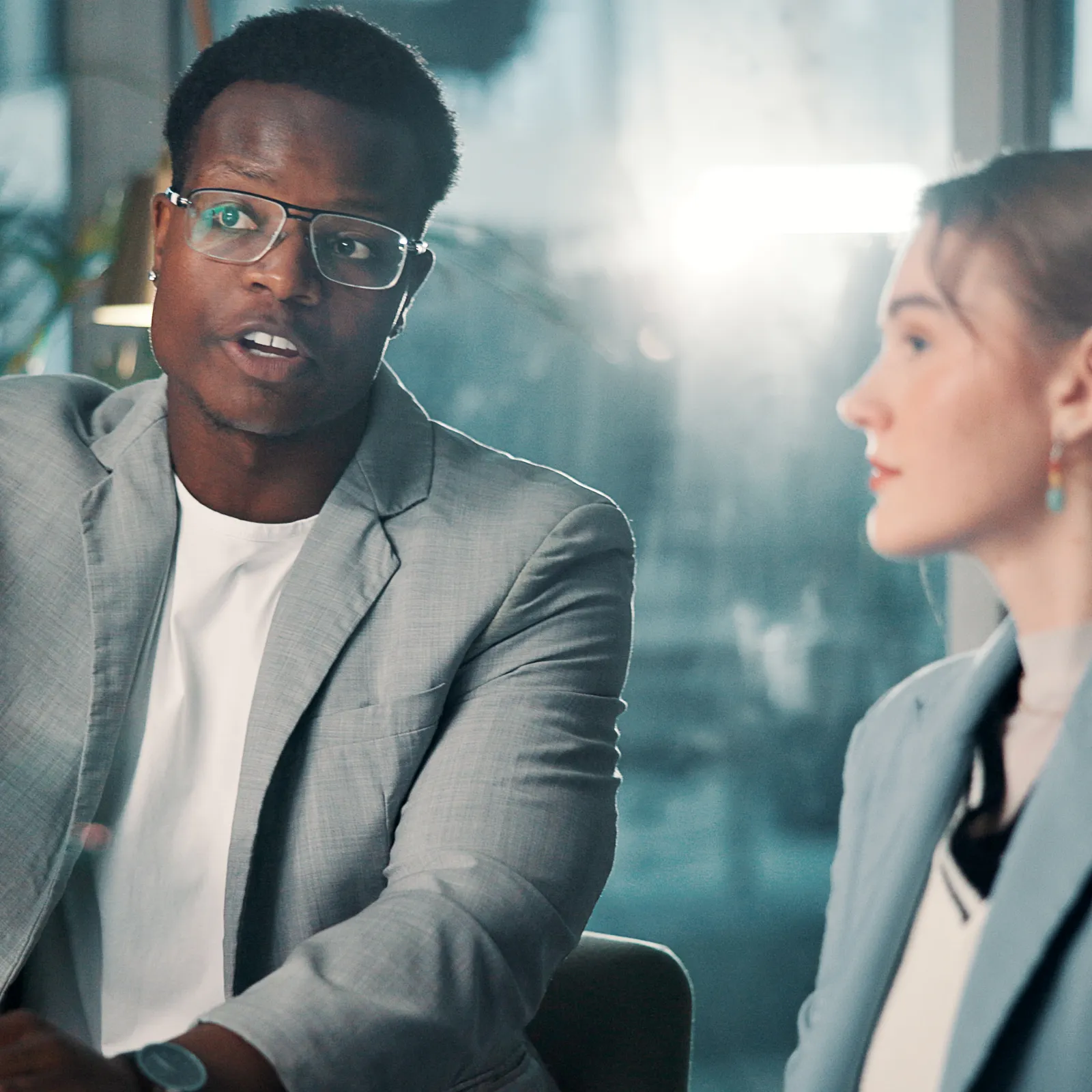 Businessman explaining a point to colleague during a meeting in a modern office with natural light.