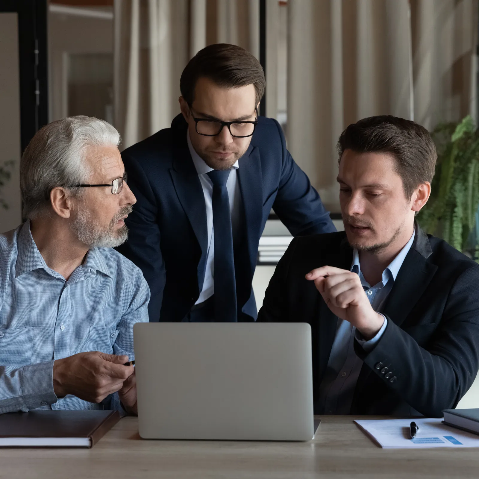 Diverse team discussing a project on machine learning in a modern office with digital screen and documents on table.