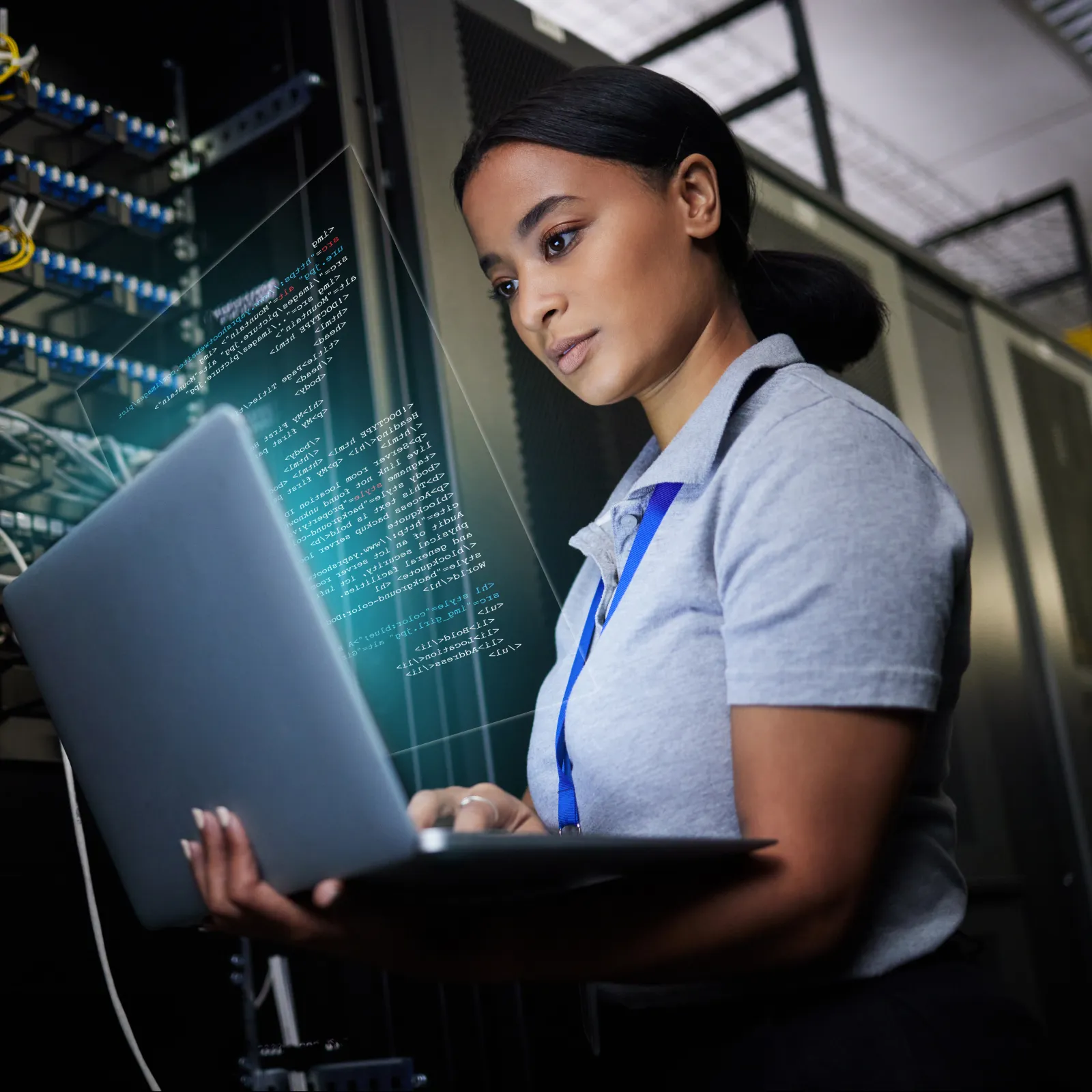 Tech professional working on laptop in server room with glowing digital code overlay