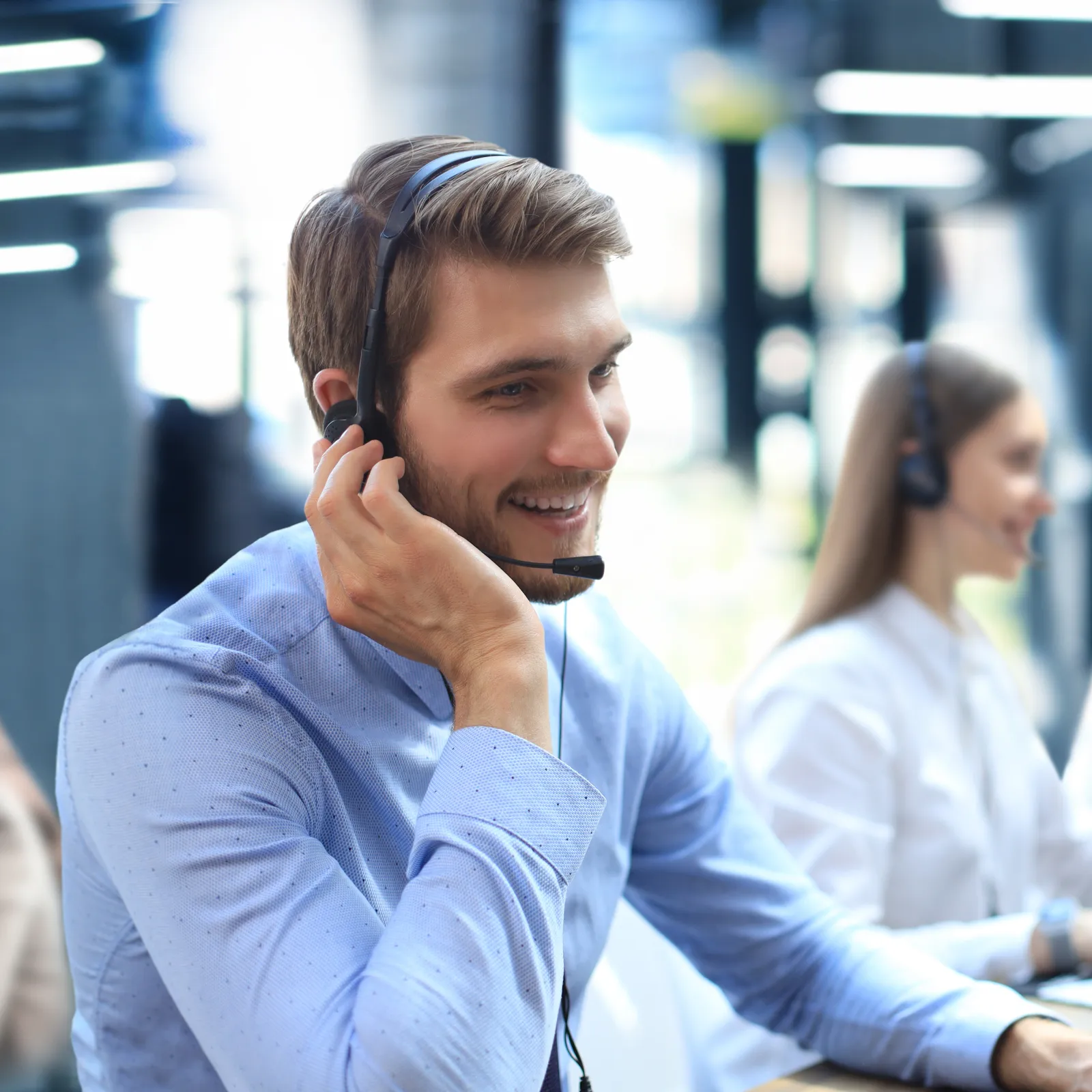 Smiling customer service team wearing headsets working at computers in bright modern office environment