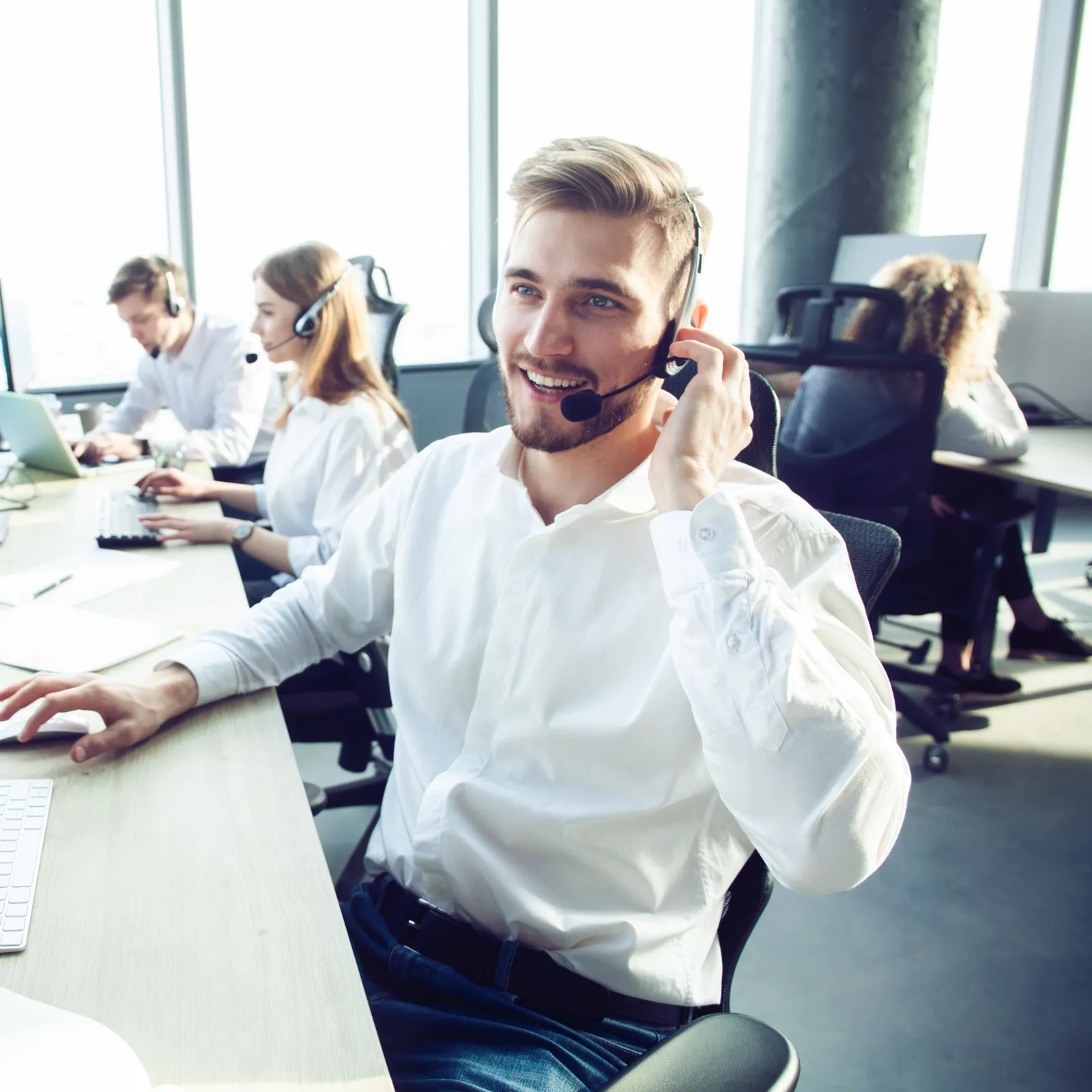Customer service team wearing headsets working on computers in a bright modern office environment