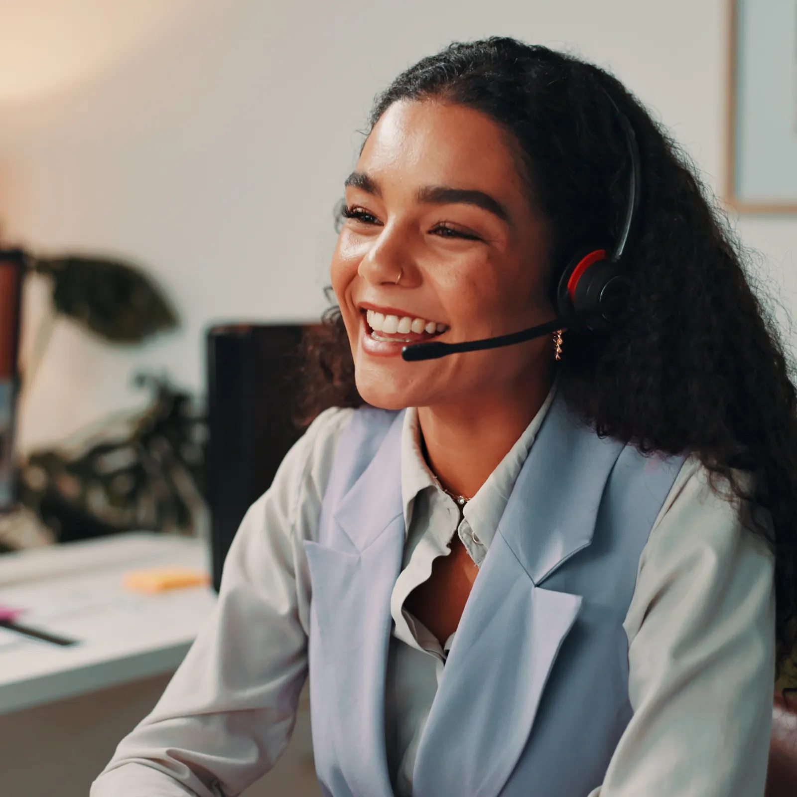 Smiling customer support representative with headset working at desk in a bright modern office environment