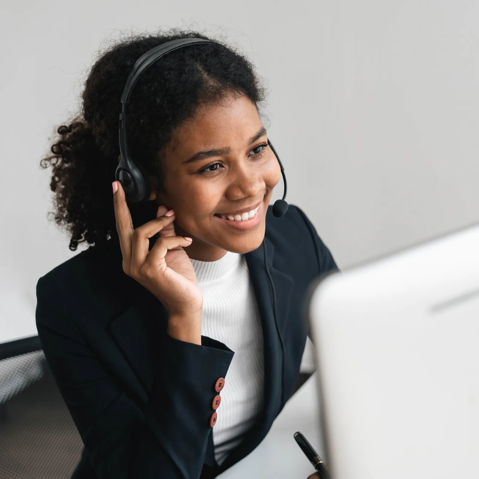 Smiling woman in headset working on computer providing customer support in modern office environment