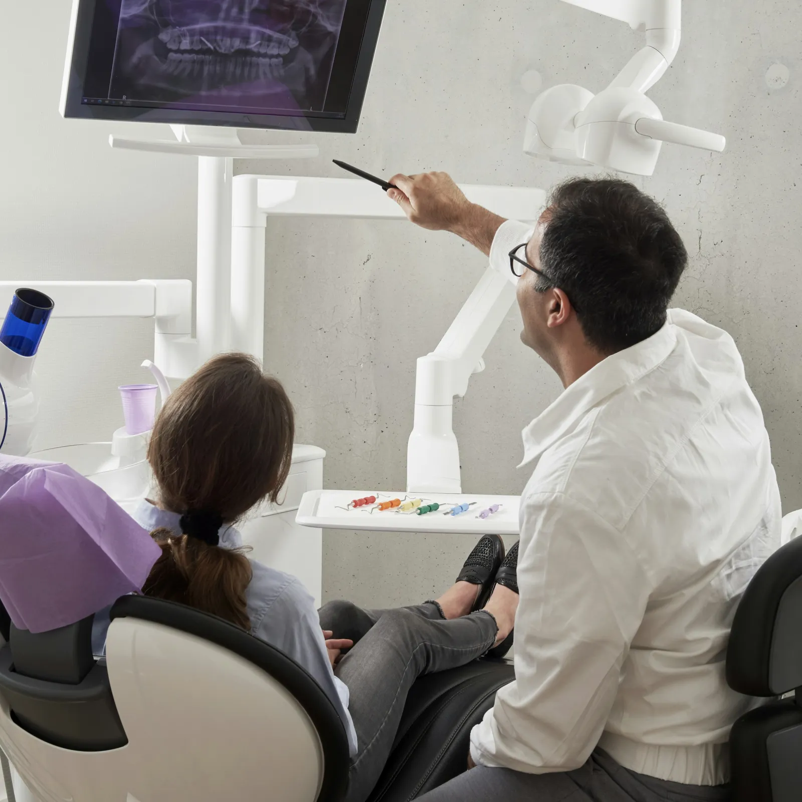 a man and a woman sitting at a table with a television and a man in a white shirt