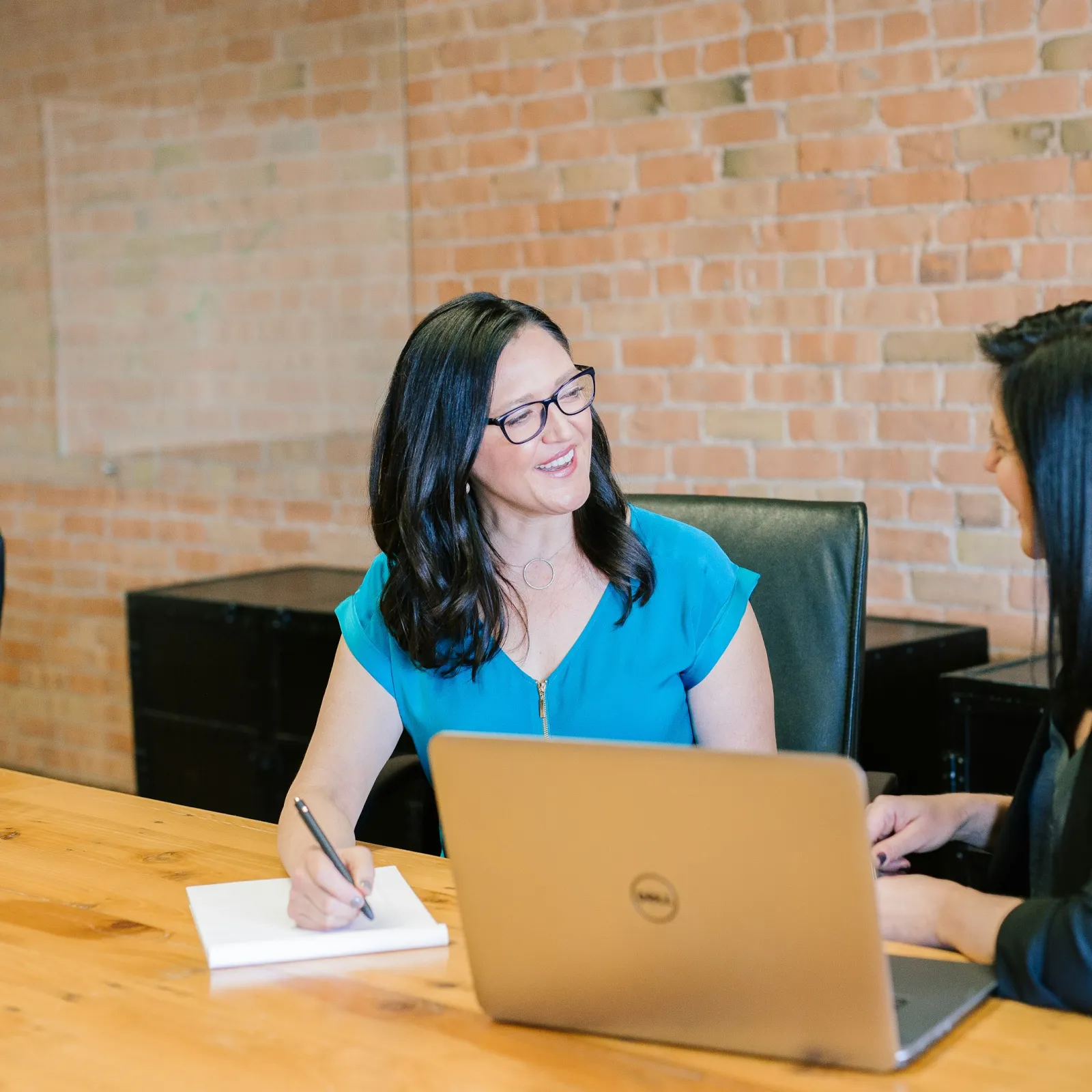 a couple of women sitting at a table looking at a laptop