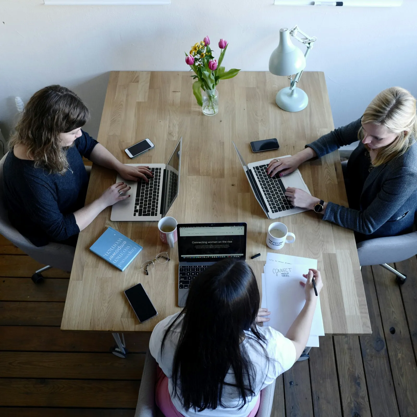 a group of women sitting around a table with laptops