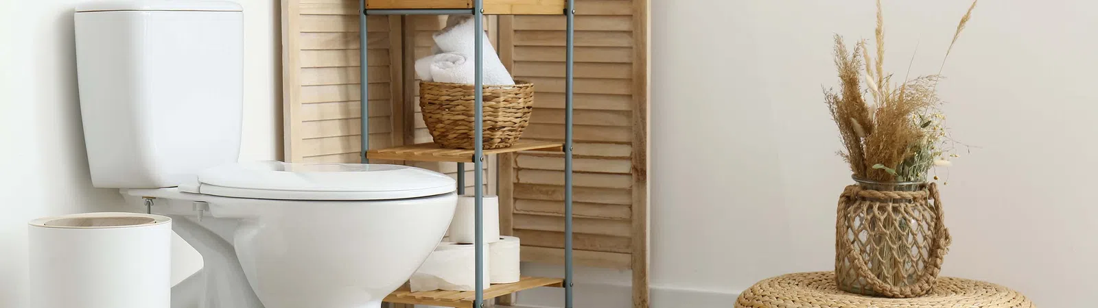 Bright white bathroom with a modern toilet, wicker baskets, wooden folding screen, and natural decor accents.