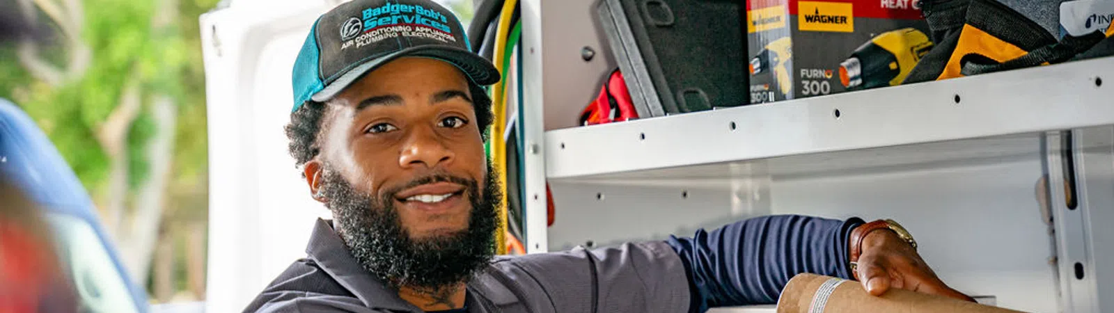 Smiling delivery worker organizing packages inside a white van with shelves and tools in the background