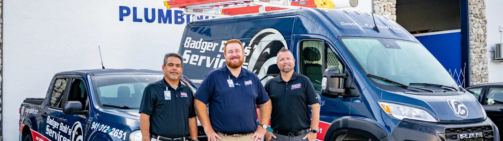 Three technicians stand in front of Badger Bob's Services vehicles and building with branded signage visible.