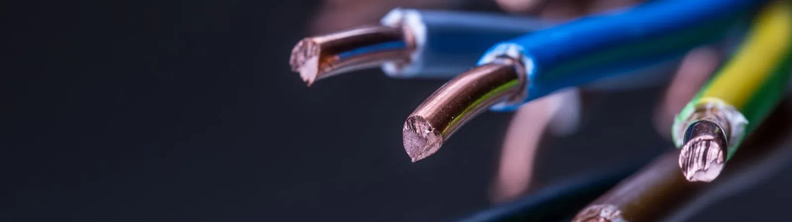 Close-up of multiple electrical wires with copper ends, showcasing vibrant insulation colors on a dark background.