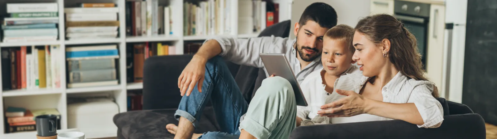 a man and woman sitting on a couch looking at a laptop