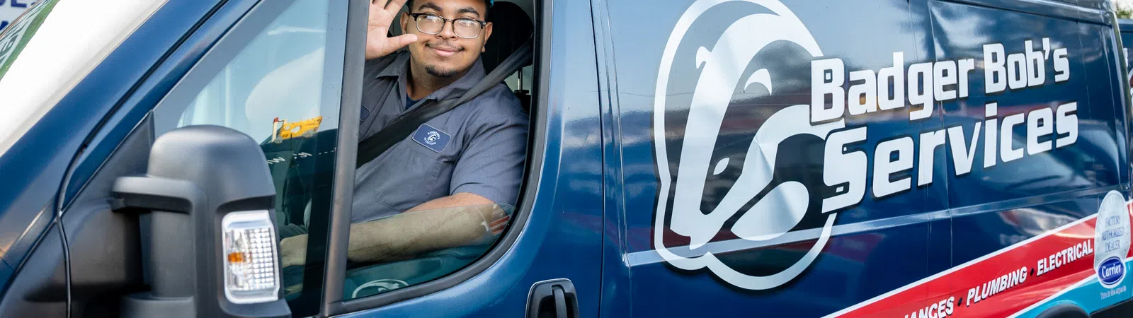 Technician waving from the driver seat of a Badger Bob's Services van with branding and contact details visible.