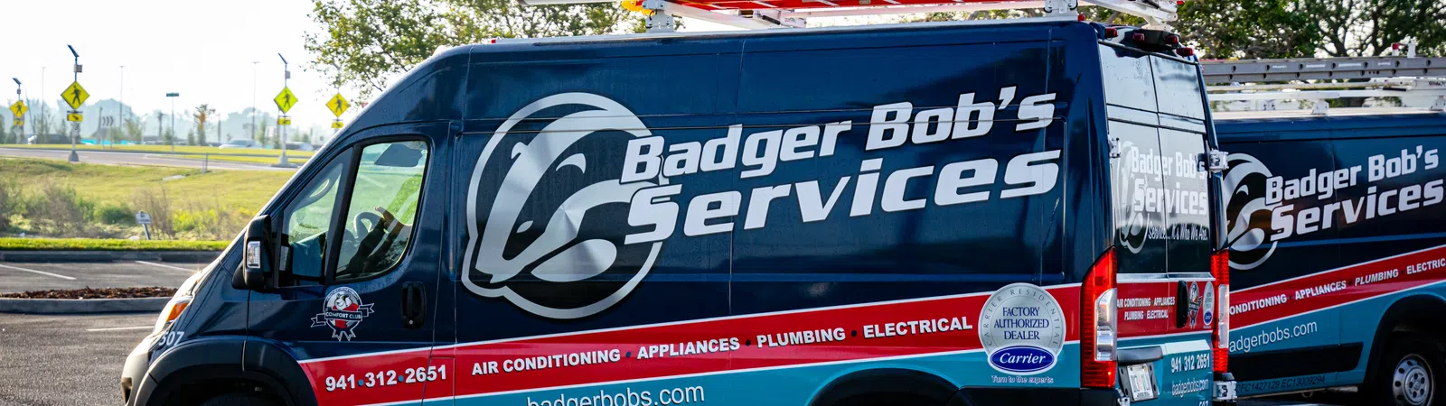 Blue Badger Bob's Services van with ladders parked outdoors advertising HVAC and plumbing services.