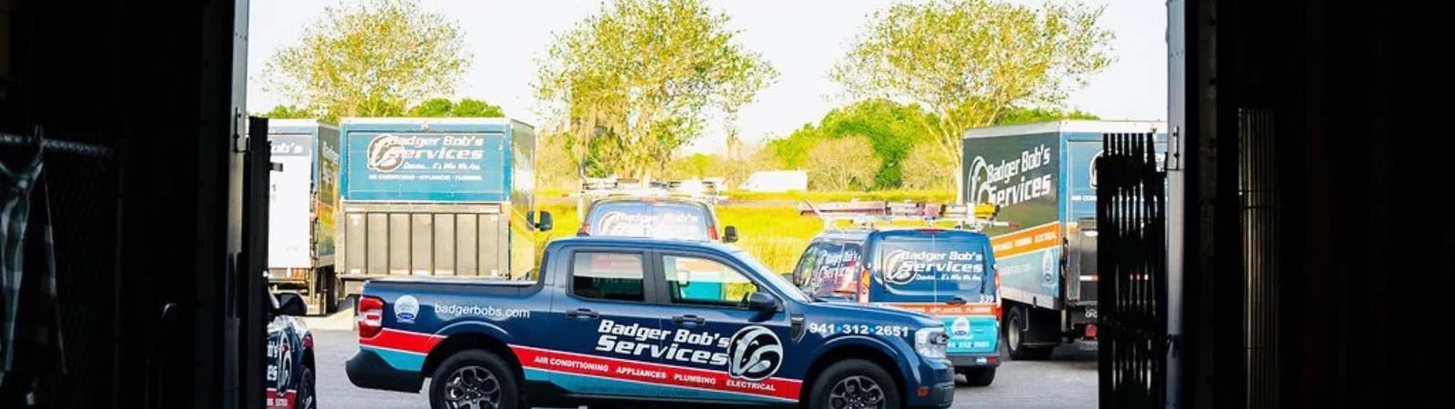 Badger Bob's Services branded trucks and vans parked outside a service garage on a sunny day.