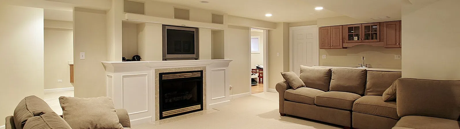 Spacious, modern basement living room with beige sofas and a cozy fireplace.