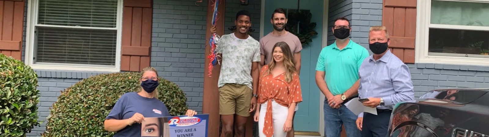 a group of people standing outside a house with balloons