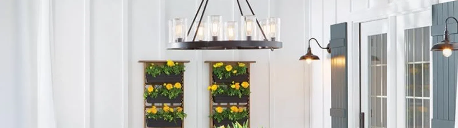 Charming dining area with a wooden table, vibrant flowers, and bright decor under a modern chandelier.