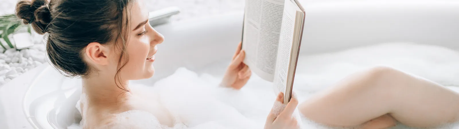 a person lying in a bathtub reading a book