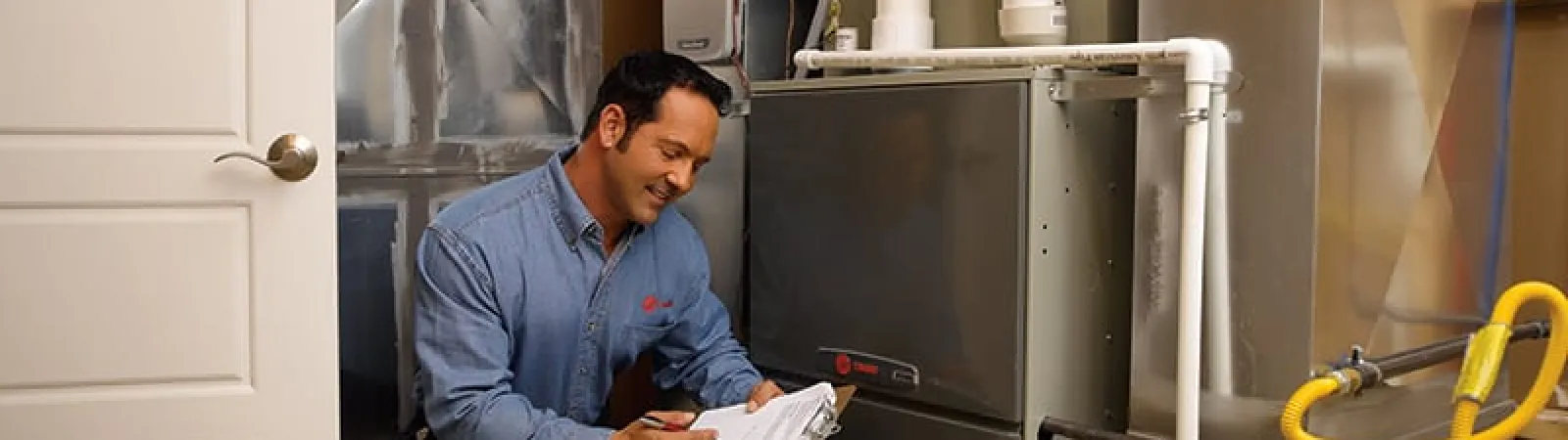 Technician inspecting a furnace, checking readings, ensuring optimal performance in a home setting.