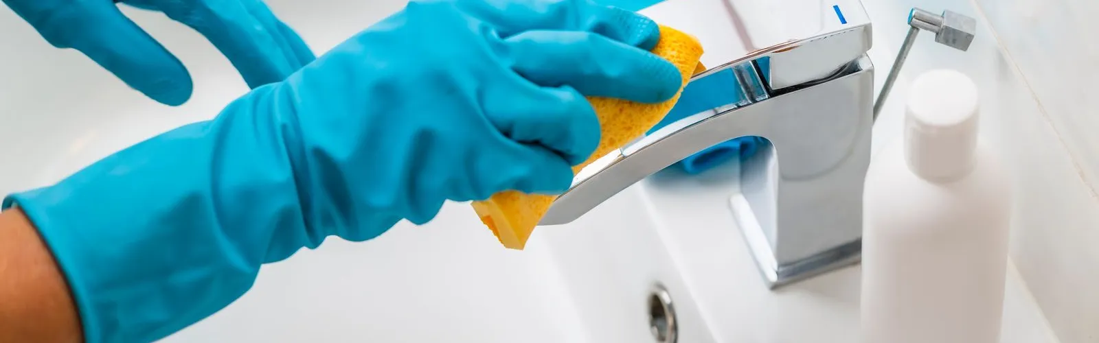 a person in blue gloves wiping sink