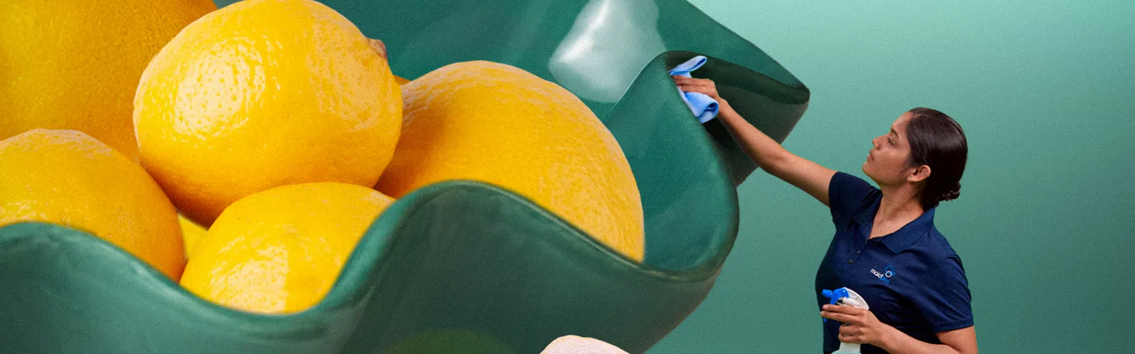 Woman cleaning an oversized green bowl filled with giant lemons and large lemon halves on mint background
