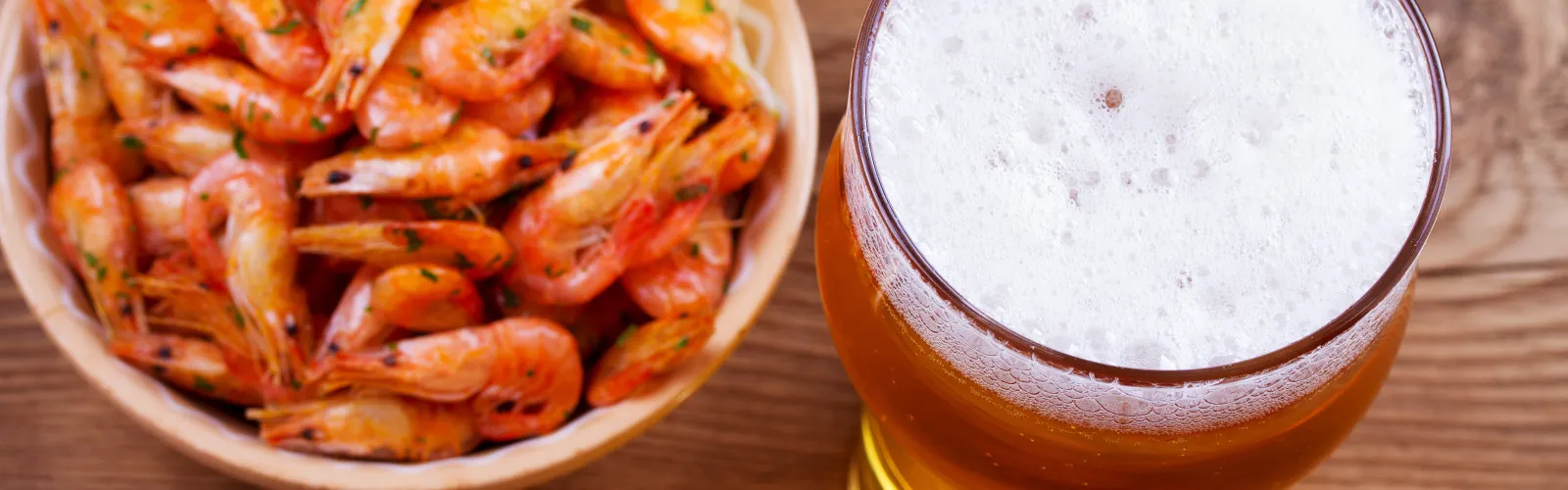 A bowl of shrimp and a glass of beer