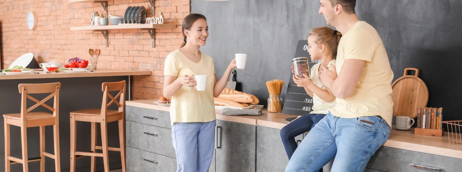 a group of people standing in a room with a brick wall and a table with a plant and