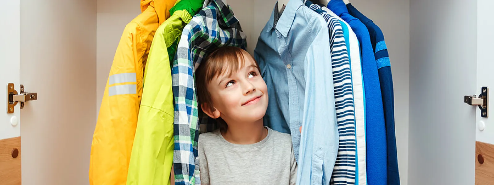 a boy standing in front of a rack of clothes