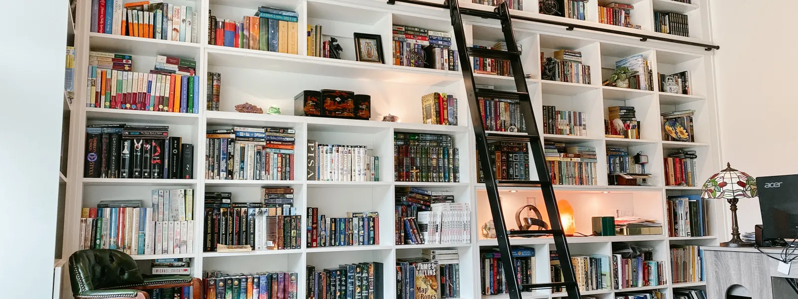 a room with shelves of books with a black ladder
