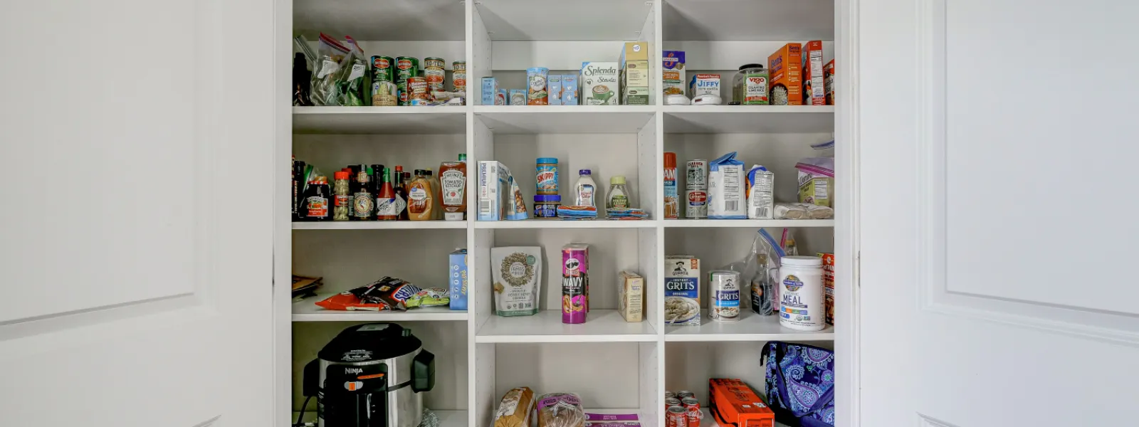 white painted pantry filled with food items and kitchen appliances