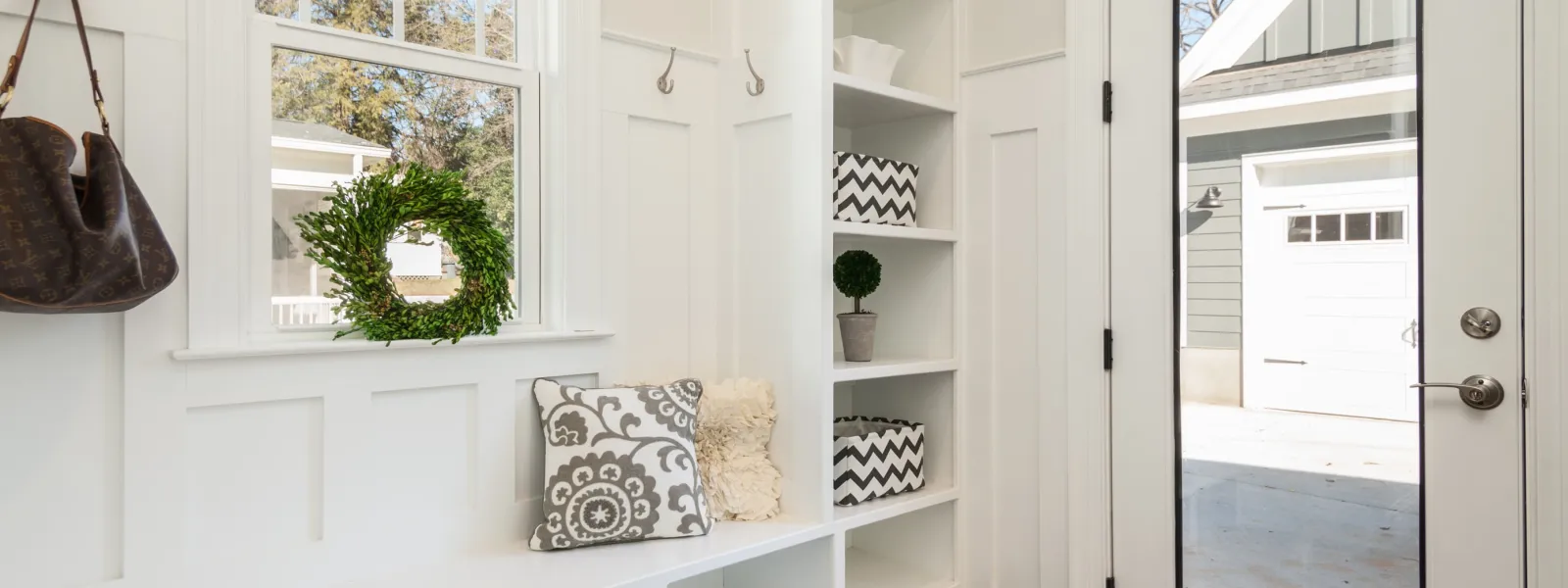 a mudroom painted white with a handbag hanging on a hook