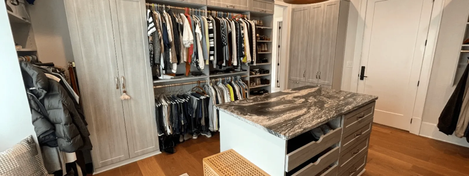 Install custom closet. Minroom with a shelf and a table with clothes on it
