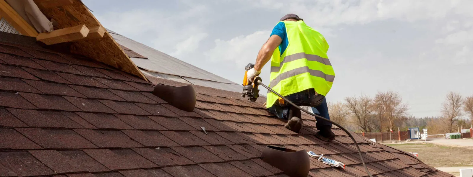 man Construction worker putting the asphalt roofing shingles on a roof