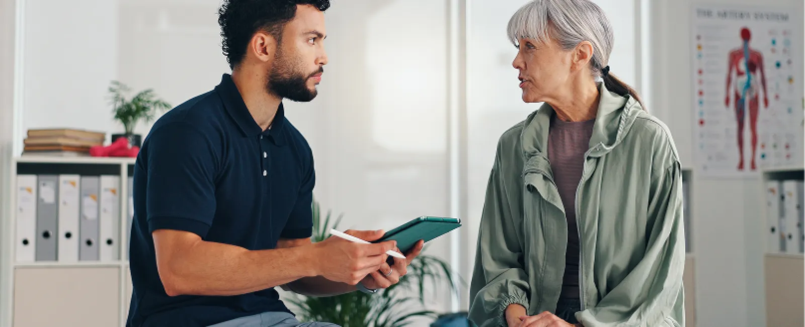 Healthcare professional consulting an elderly woman in a medical office discussing health concerns.