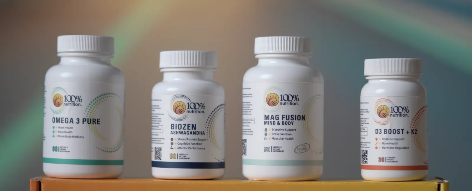 Four 100% Nutrition supplement bottles including Omega 3 Pure, BioZen Ashwagandha, Mag Fusion, and D3 Boost + K2 on a yellow box.