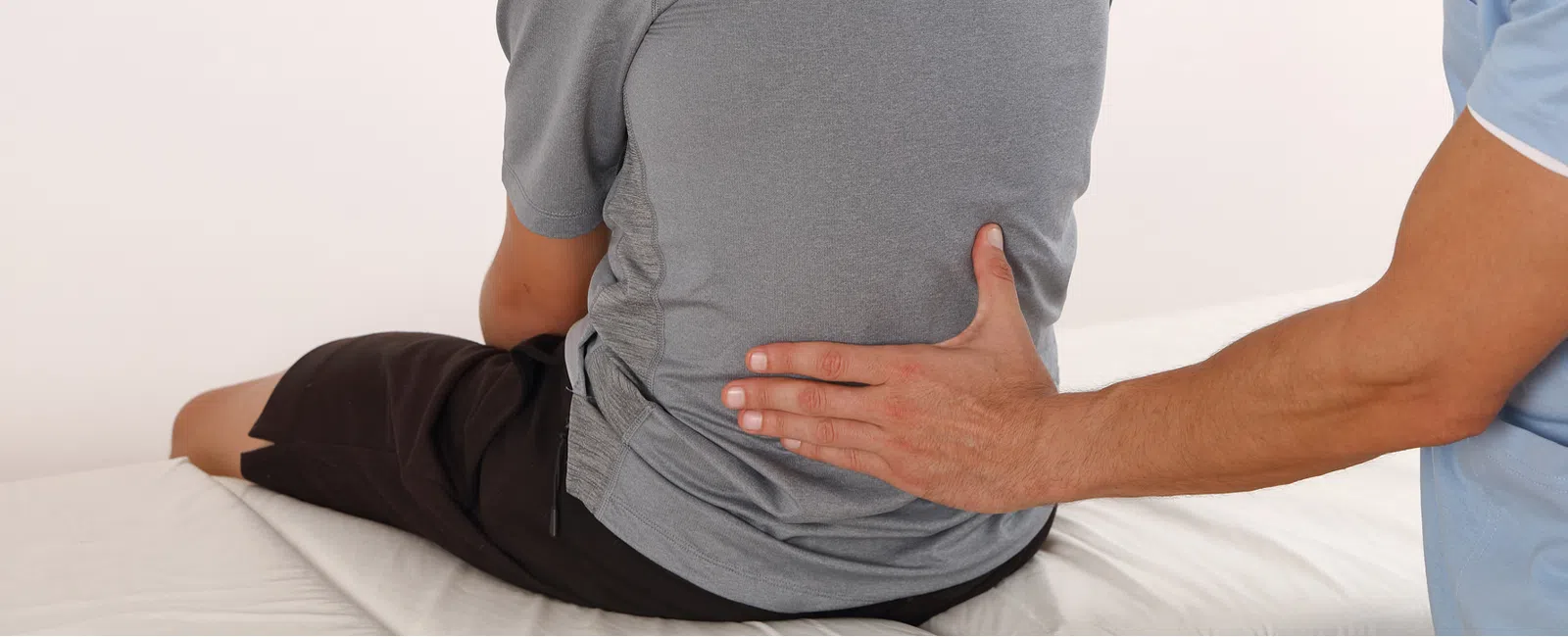 Chiropractor providing back treatment to patient sitting on medical table in clinic