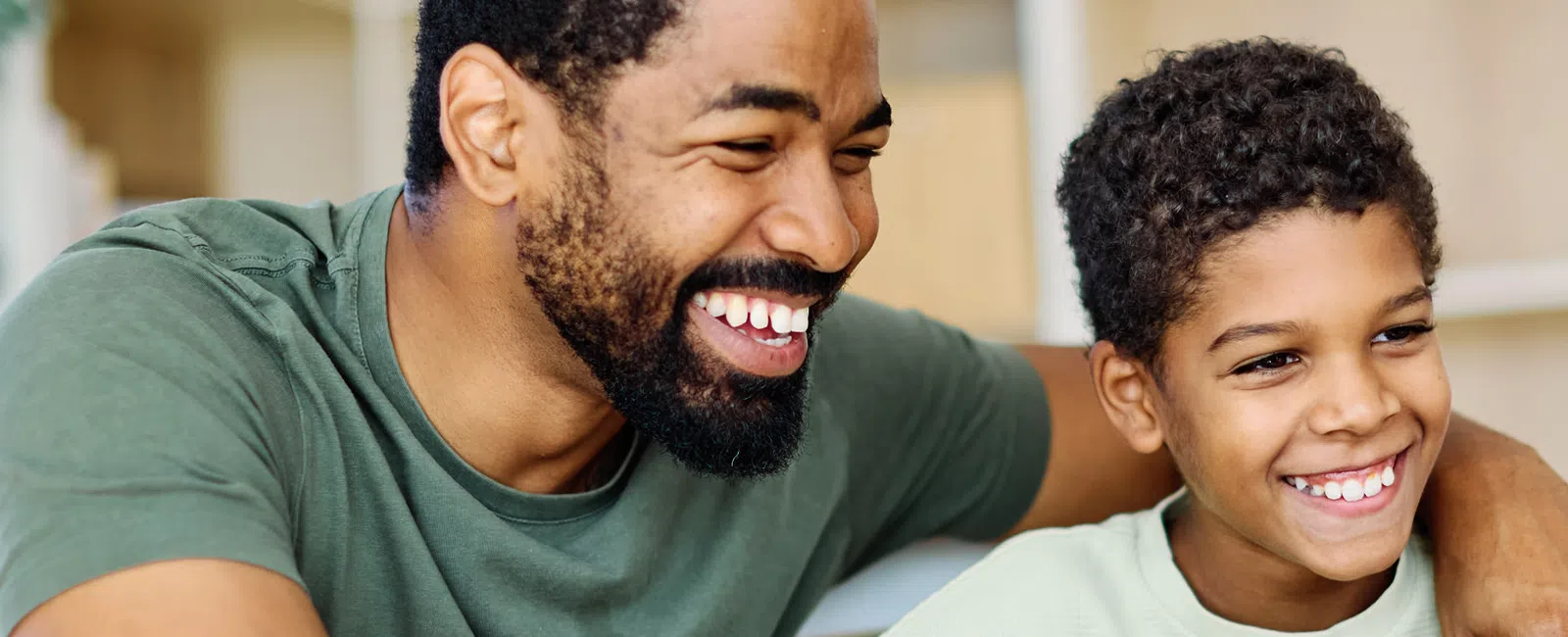 Happy father and son smiling and looking at a laptop screen together at home