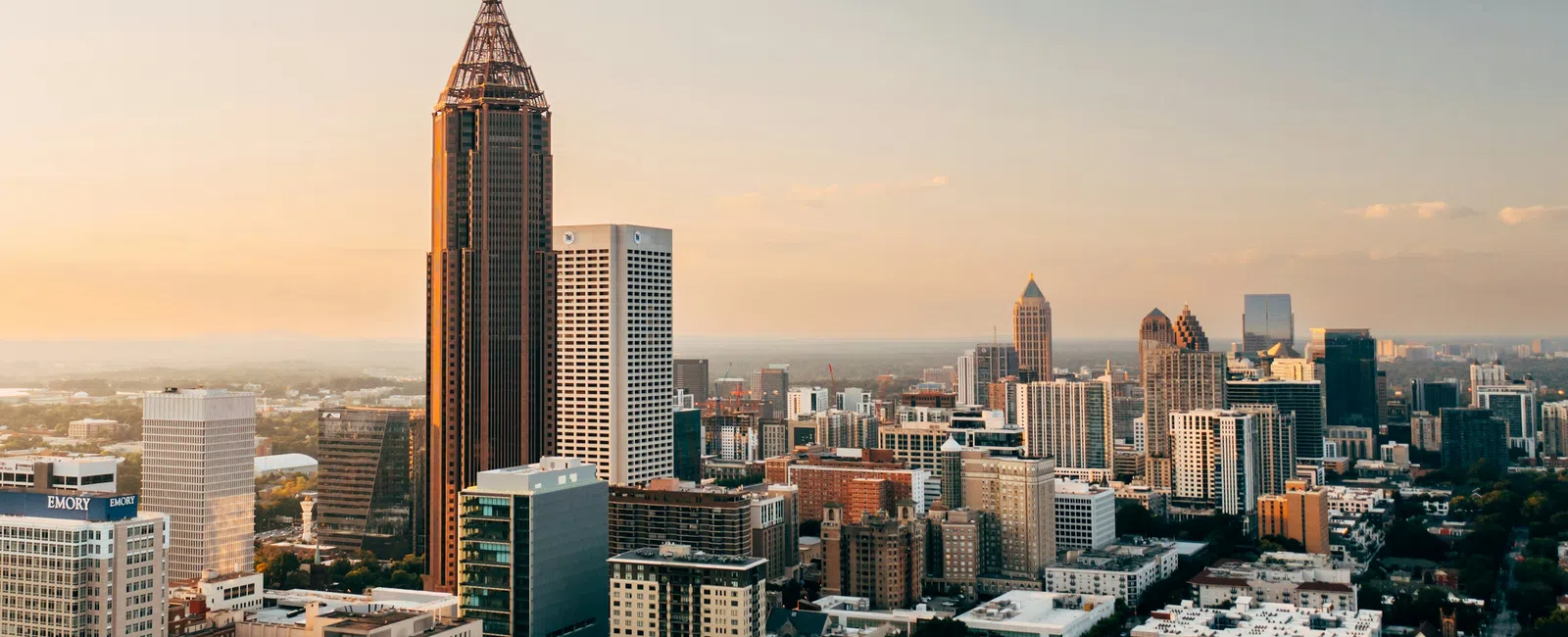 Downtown Atlanta skyline at sunset with prominent skyscrapers and urban buildings under a clear sky.