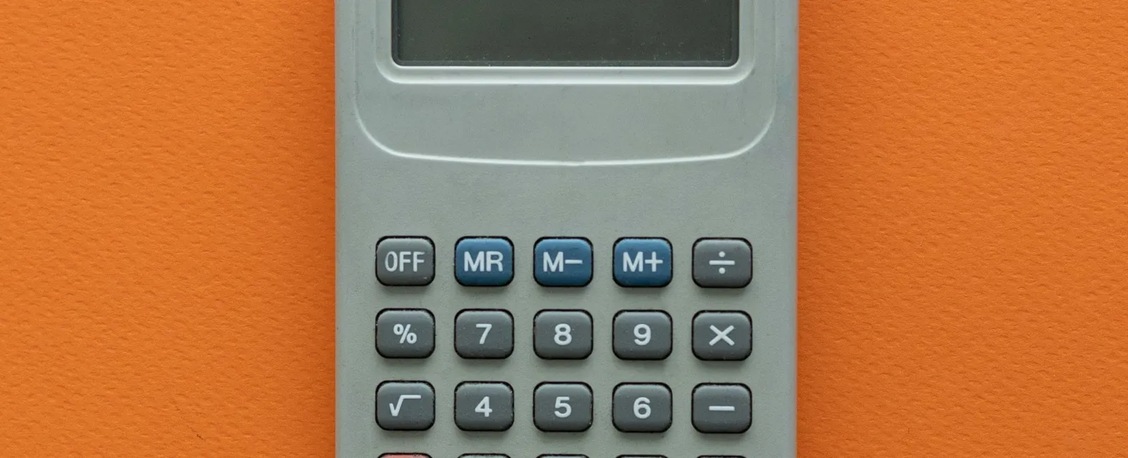 Gray calculator with blue and red buttons on an orange textured background, centered in the frame.