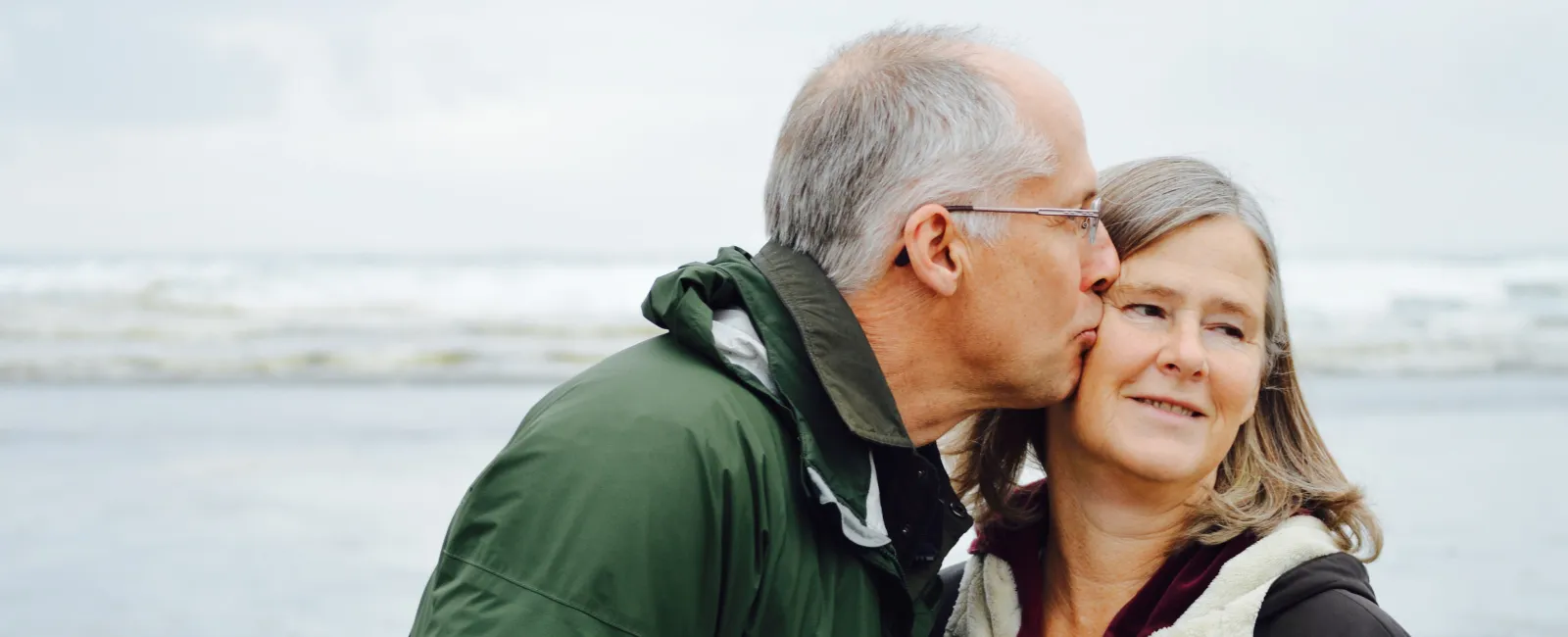 a man and woman kissing on a beach