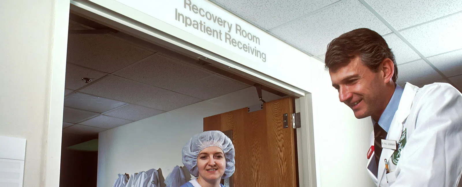 Doctor and nurse attending to a patient in a hospital recovery room, showing medical care and support.