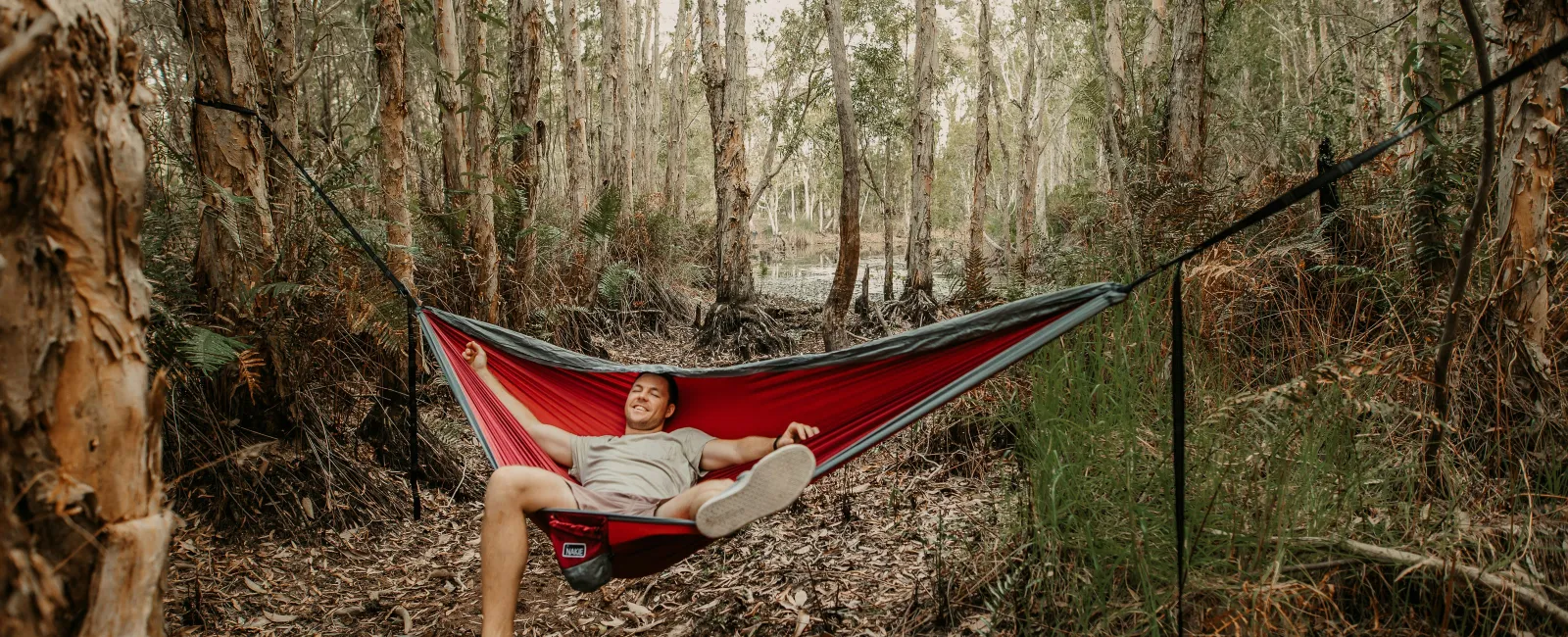 a person lying in a hammock in the woods