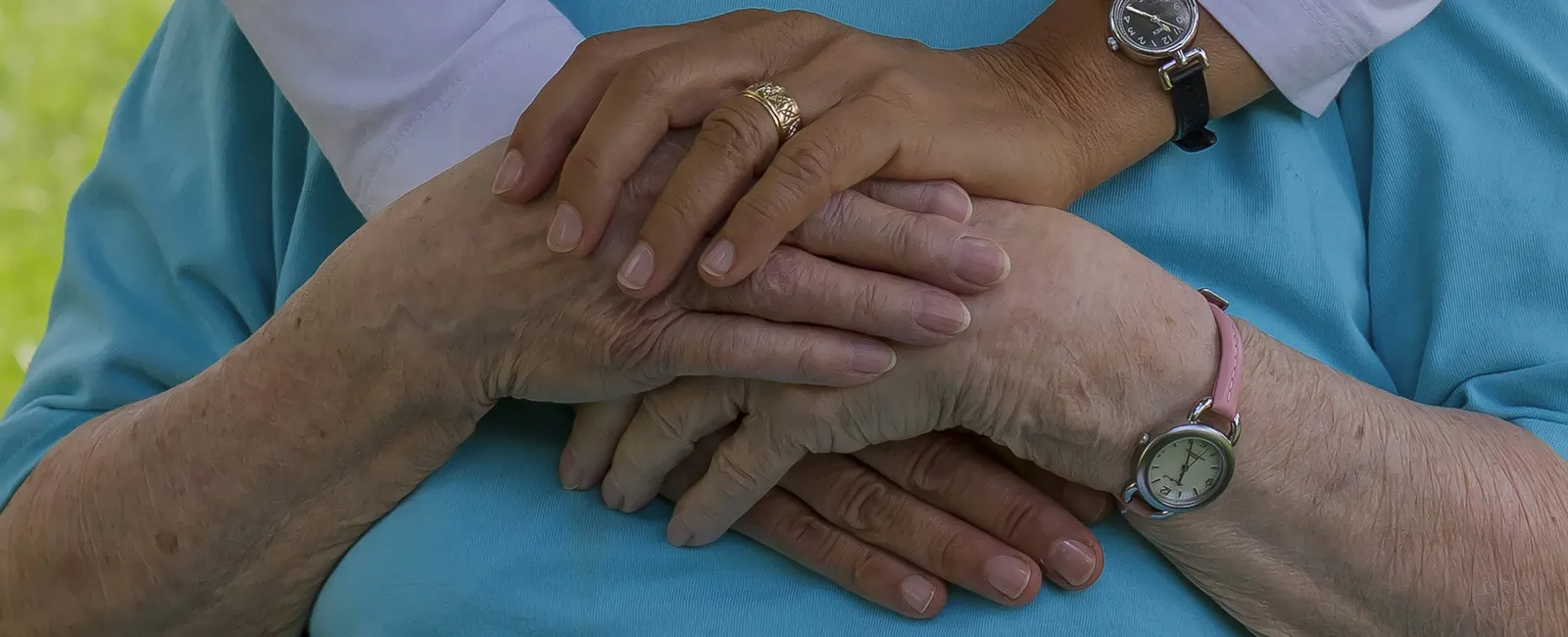 Close-up of two people embracing with hands gently clasped, showing care and support.