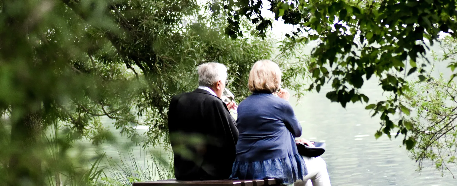 a group of people sitting on a bench by a river