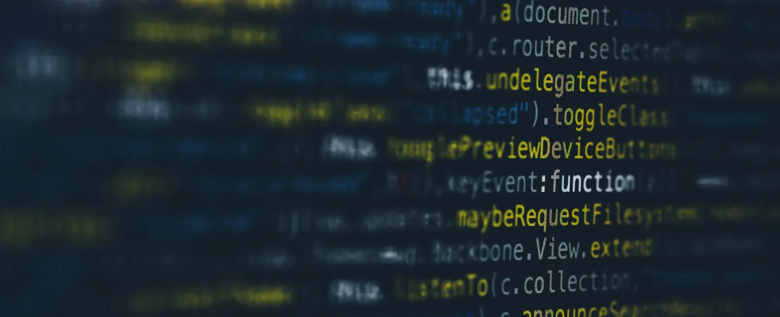 Close-up of blurred computer code on screen with yellow and white syntax highlighting.