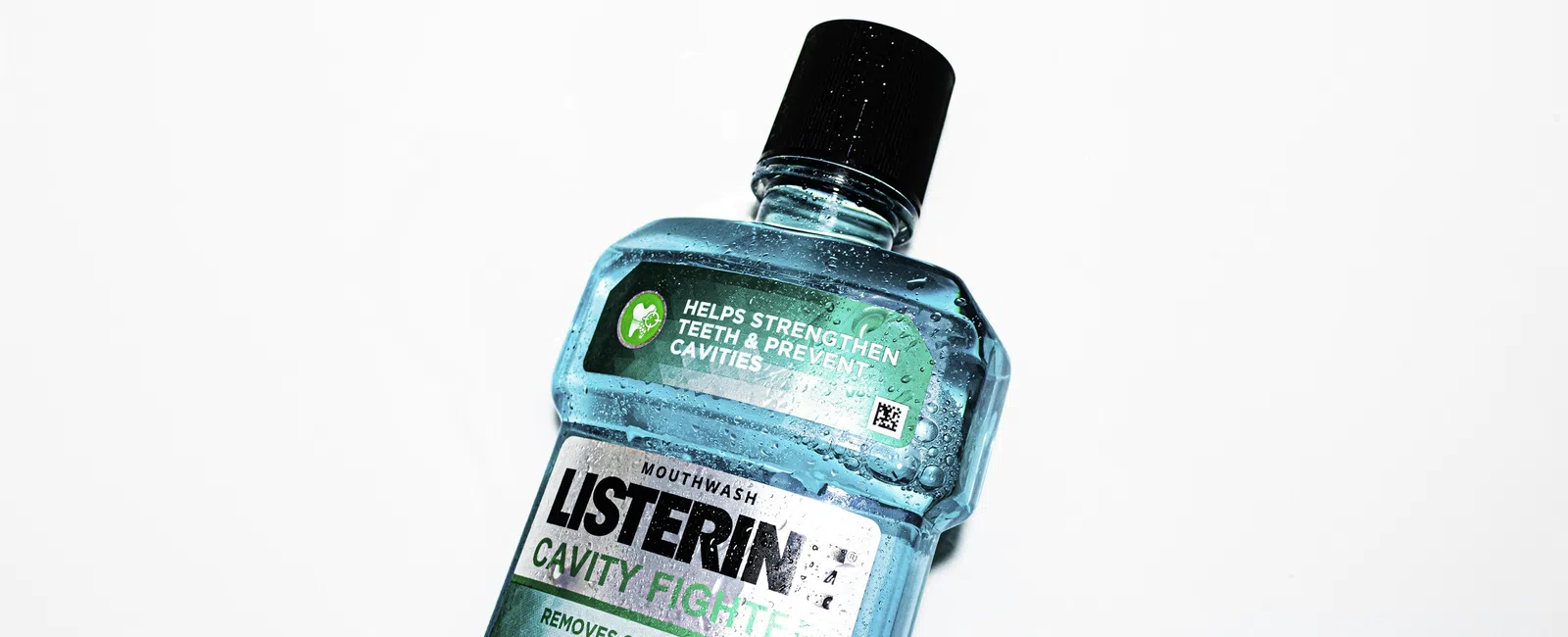 Blue Listerine mouthwash bottle against a white background highlighting cavity fighting and germ removal benefits.
