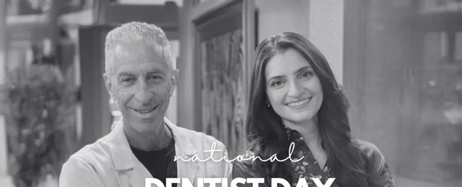 Smiling male dentist in white coat and female colleague celebrating National Dentist Day together indoors.