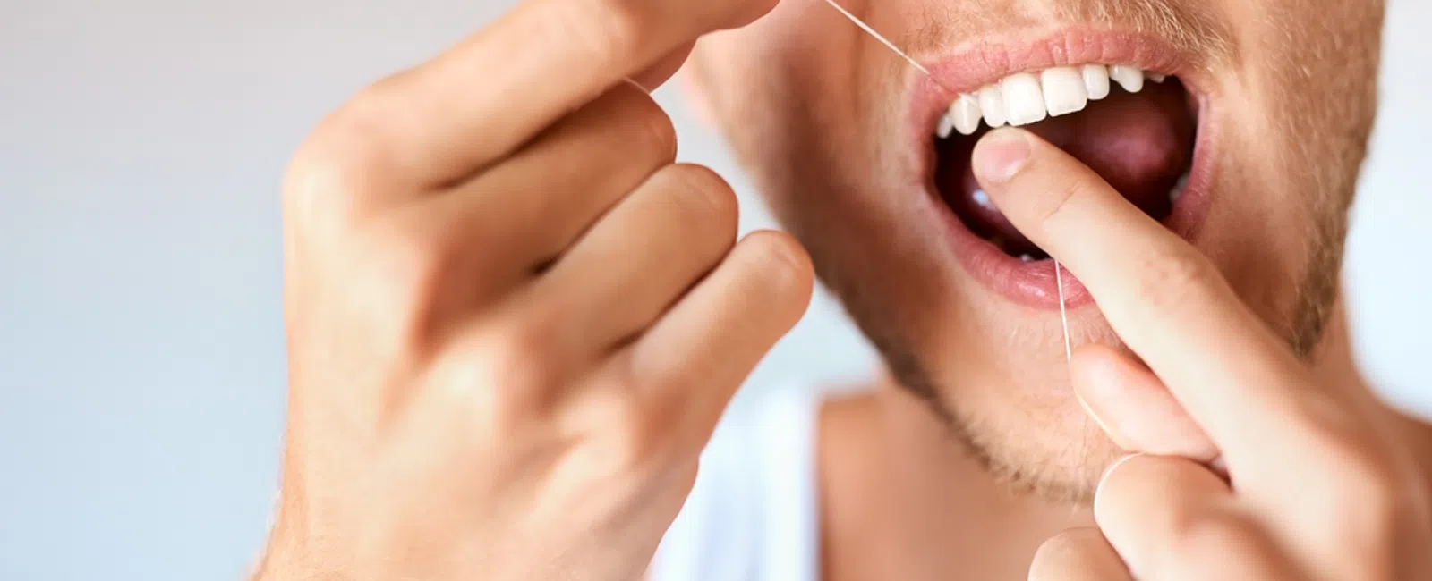 Close-up of a man flossing his teeth showing dental care and hygiene routine.