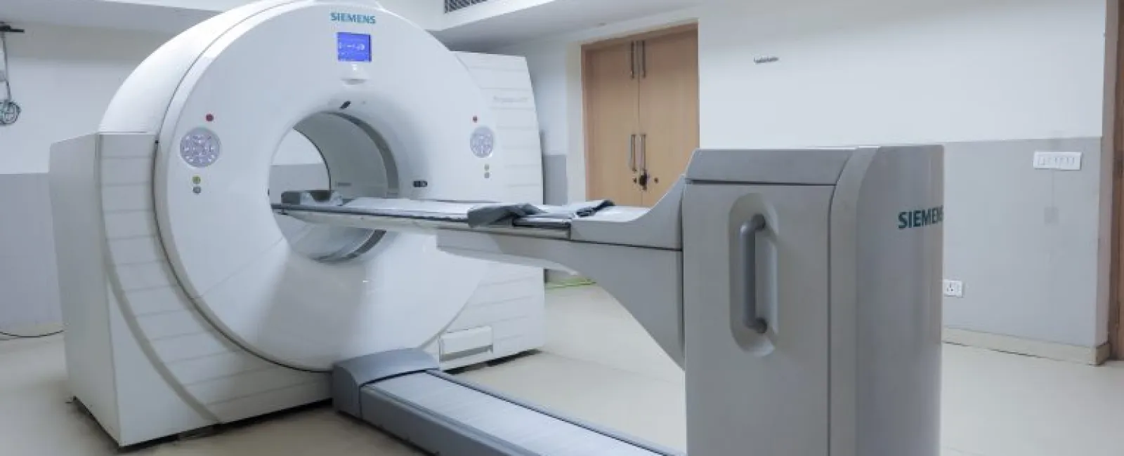 Siemens MRI scanner in a clean hospital room with white walls and tiled flooring